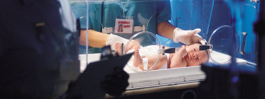 Medical professionals with preterm baby in incubator