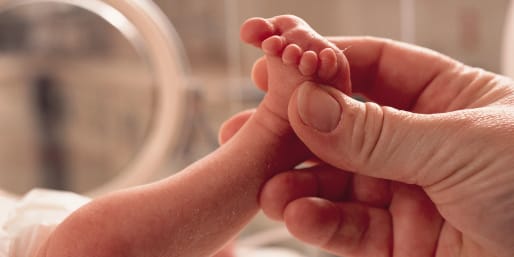 Parent holdIng foot of preterm baby