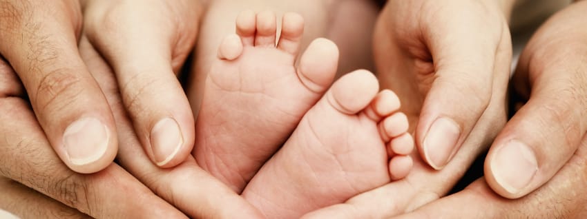 Parent hands supporting baby feet