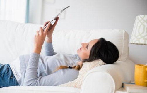 Pregnant woman lying on sofa using tablet device