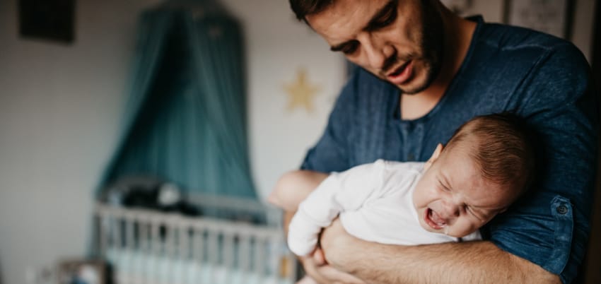 Parent holding infant suffering from reflux