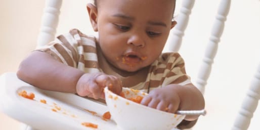 Baby eating with fingers from bowl