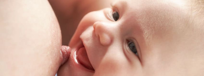 Smiling baby breastfeeding