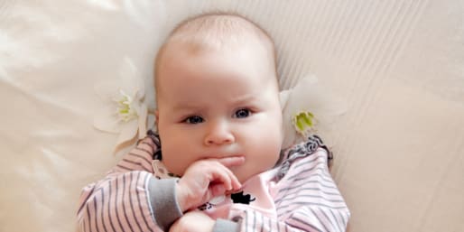 baby-lying-on-back-biting-finger