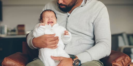 Crying baby upright in dads arms