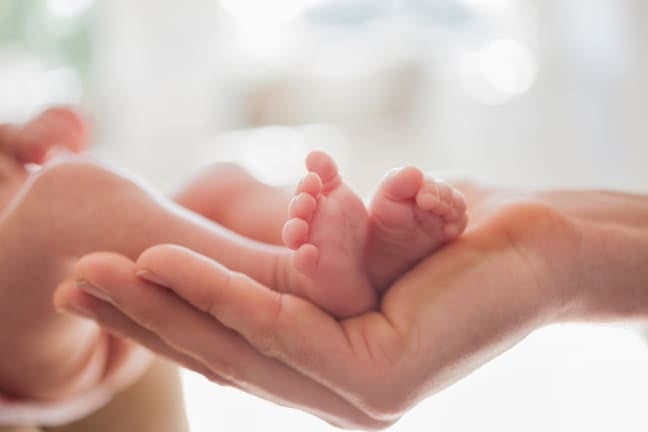 Adult hand supporting preterm baby feet
