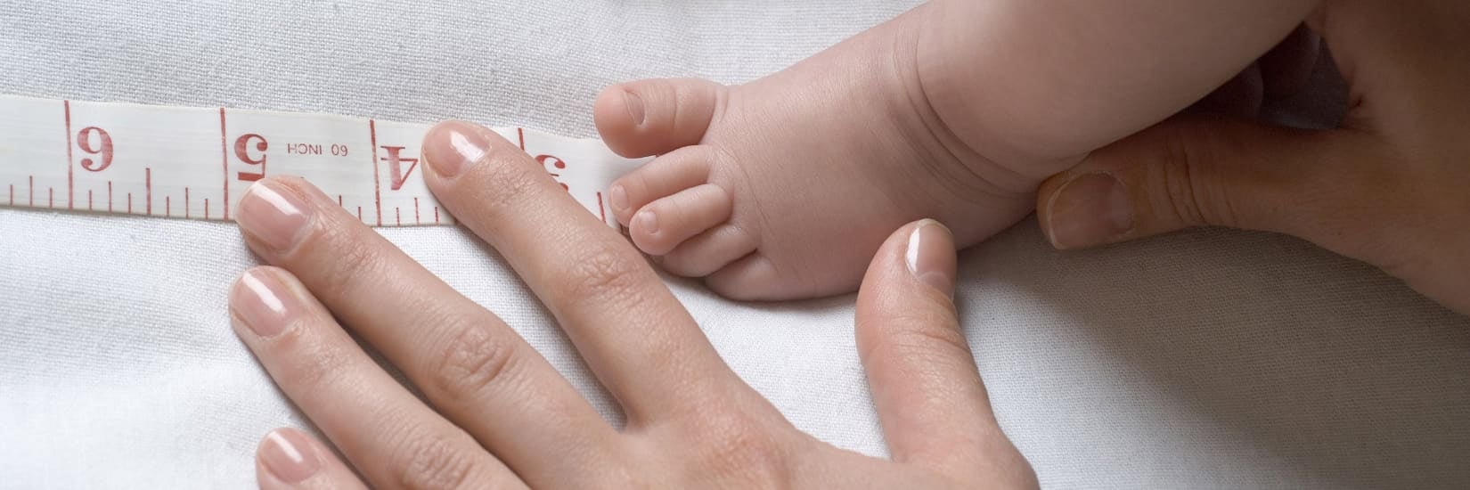 Mother gently holding up her baby's feet, symbolizing care and support for healthy infant development and growth.