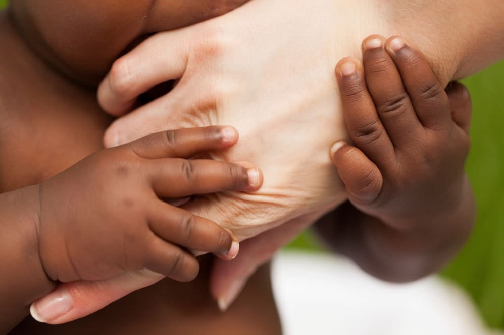 Baby's hand holding adult's finger, symbolizing the vital role of healthcare professionals in infant care and development