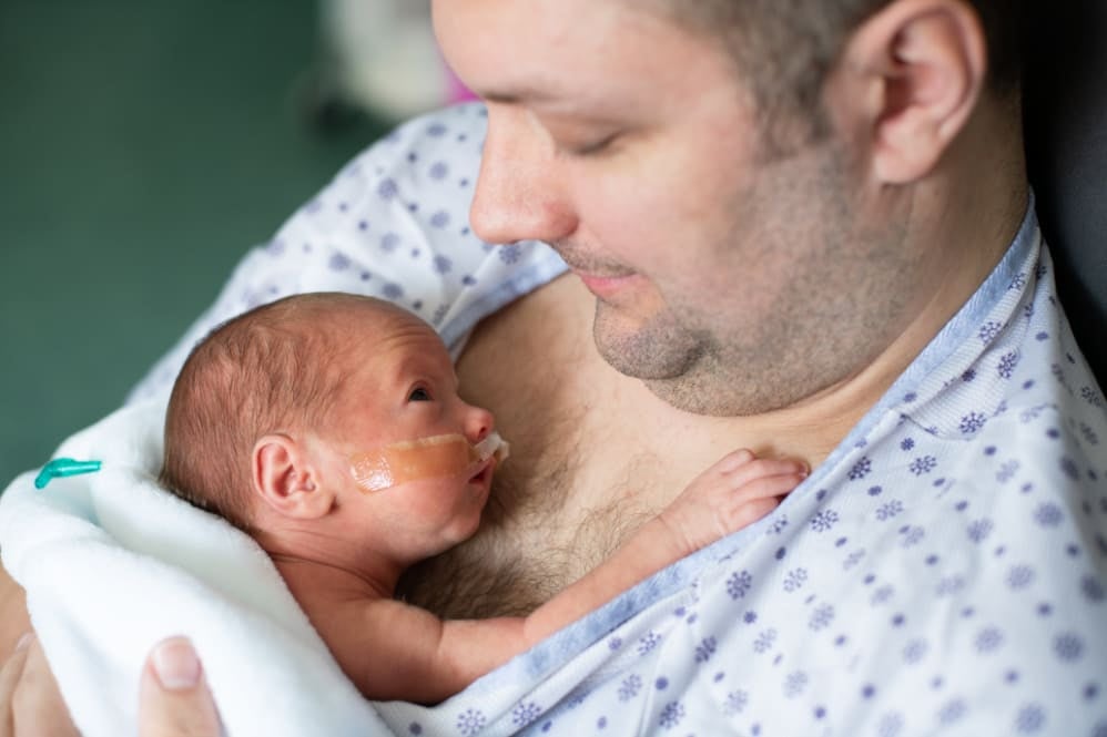 Father gently holding his preterm baby