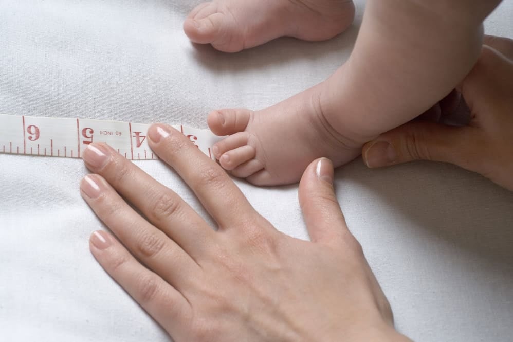 A parent measuring their child's foot: a symbolic gesture representing faltering growth