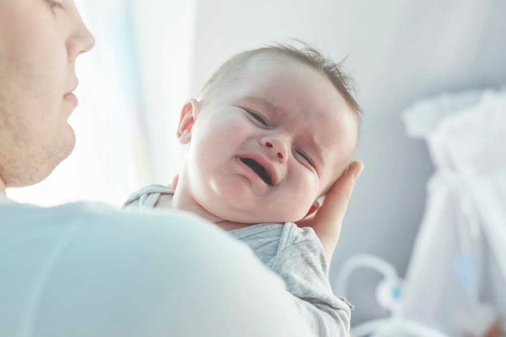 A parent holding their crying newborn 