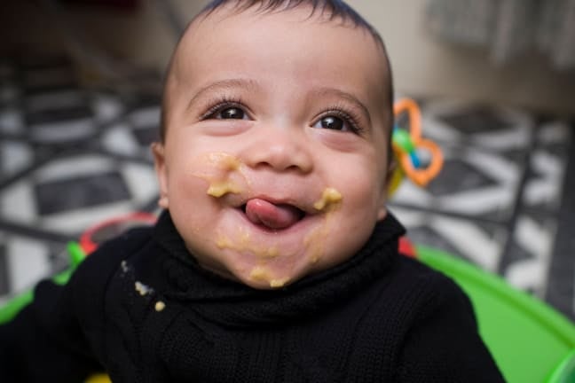 Baby boy eating in high chair