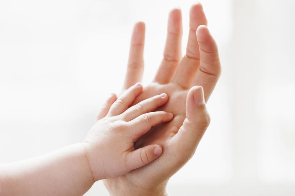 Close-up of a baby's hand resting on an adult's palm
