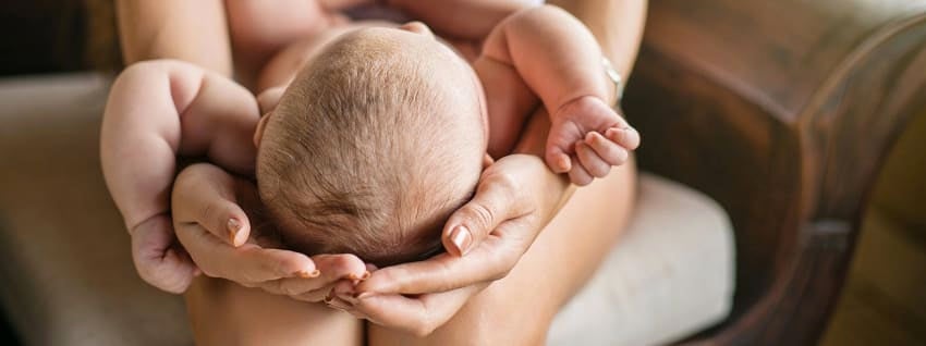 Mother cradling babies head on her lap