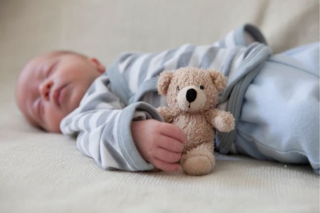 Baby asleep holding teddy