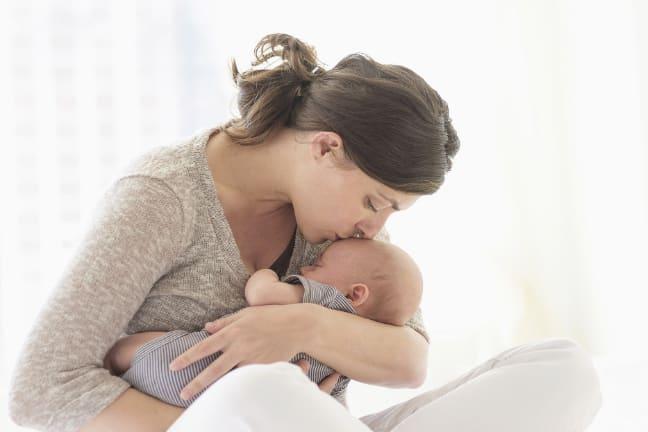 A mother cradling and kissing her baby