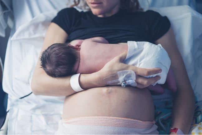 Mother breastfeeding her newborn baby in a hospital bed